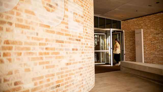 Brick building with glass double doors and a person visible inside.