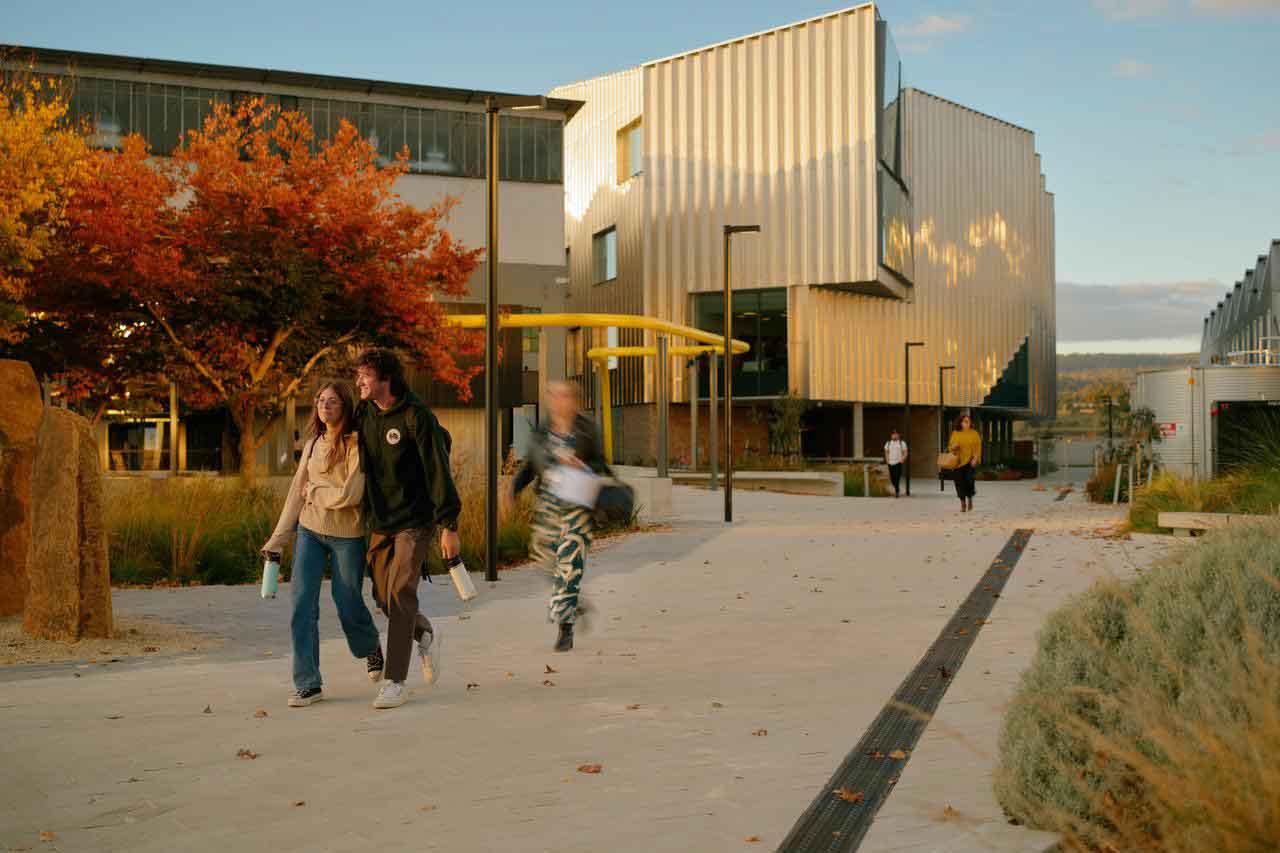 Students walking among Inveresk campus and surrounds with autumn foliage.