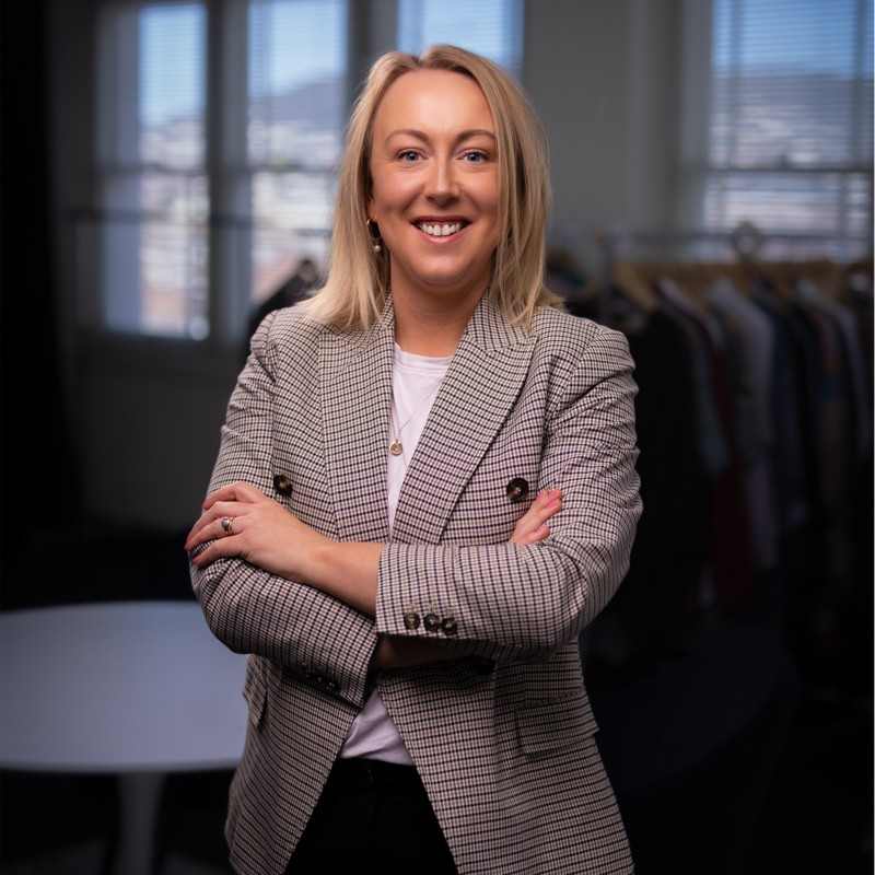 Dress for Success CEO and University of Tasmania graduate Amanda French, a blonde woman in a grey blazer stands smiling with her arms crossed. (Picture supplied by Amanda French)